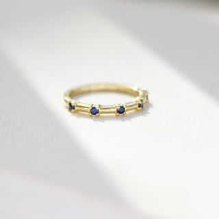 Gold ring with blue stones on a light gray background