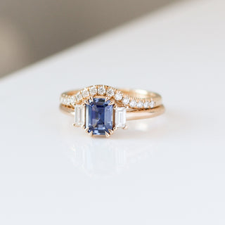 Blue emerald cut sapphire and diamond ring on white background stacked with curved diamond pave band, front view