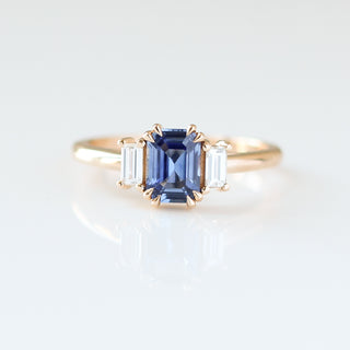 Blue emerald cut sapphire and diamond ring on white background,  front view