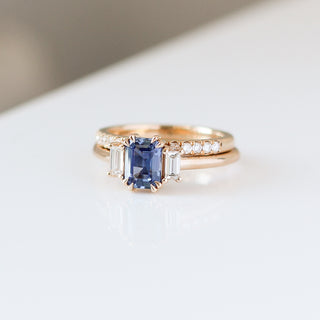 Blue emerald cut sapphire and diamond ring on white background stacked with pave diamond straight band, front view