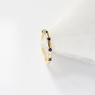 Gold ring with blue stones on a white back marble