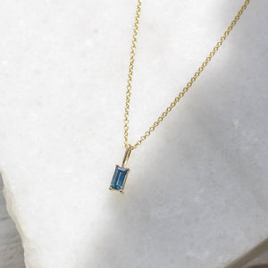 Blue Sapphire Baguette Cut Pendant on chain on marble side view