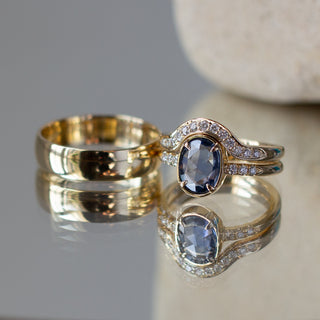 Custom wavy wedding band and engagement ring set with ethically sourced diamonds and sapphire in a gold setting, handcrafted by Yuliya Chorna at her Toronto studio.