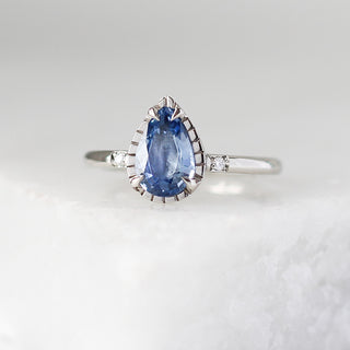 Custom engagement ring with ethically sourced blue pear sapphire centre stone in a platinum setting, handcrafted by Yuliya Chorna at her Toronto studio.