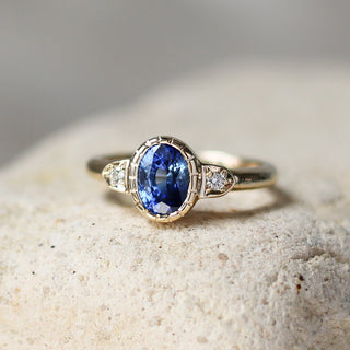 Custom engagement ring with ethically sourced blue sapphire centre stone in a gold setting, handcrafted by Yuliya Chorna at her Toronto studio.