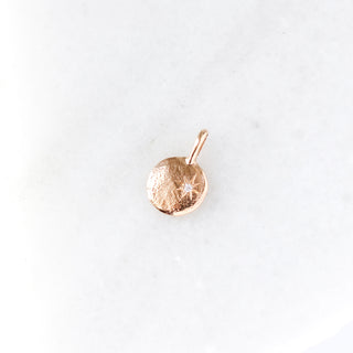 Yellow gold pendant with a diamond on a white background
