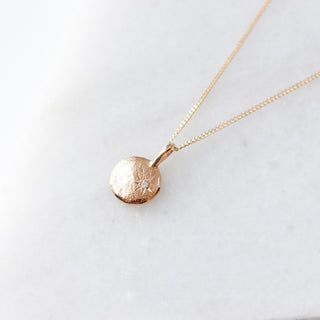 Gold necklace with a round pendant on a white background