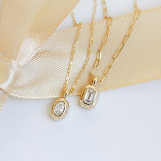 Two gold necklaces with diamond pendants on a white background