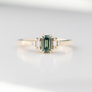 Gold ring with a green gemstone on a light gray background
