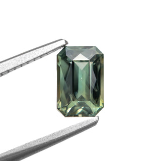 Green radiant cut sapphire on white background, held by tweezers