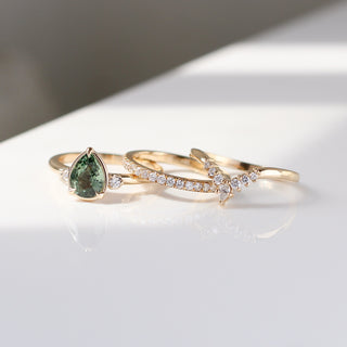 Pear cut green sapphire engagement ring styled with diamond bands on white