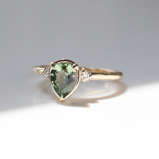 Pear cut green sapphire engagement ring quarter view in the sun