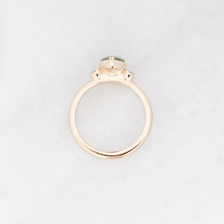 Three stone engagement ring with a green pear cut sapphire in yellow gold, side profile view