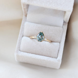 Three stone engagement ring with a green pear cut sapphire in yellow gold, in ring box
