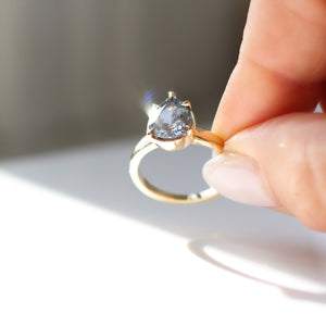 Pear pale blue sapphire engagement ring in hand in sunlight