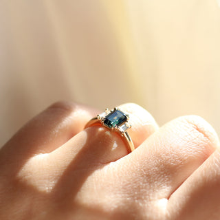 Emerald cut green sapphire engagement ring in sunlight on hand