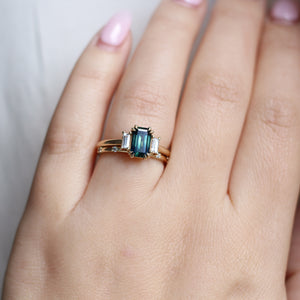 Emerald cut green teal sapphire engagement ring with diamond wedding band on hand