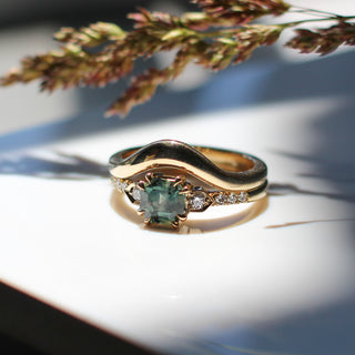 Cut Corner Rectangle Step Cut Green Sapphire Ring paired with gold wave band and grains detailed view in sunlight 