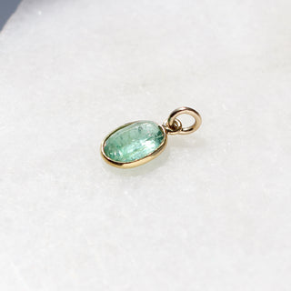 Large Emerald Bezel Charm quarter side view on marble 