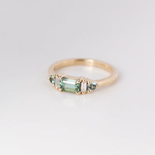 Yellow gold ring with a teal green emerald cut sapphire, quarter view
