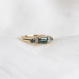 Yellow gold ring with a teal green emerald cut sapphire, quarter view