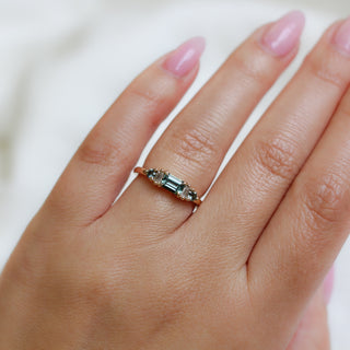 Yellow gold ring with a teal green emerald cut sapphire, on hand