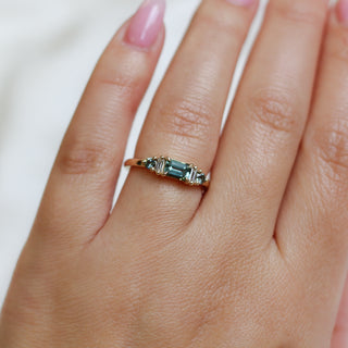 Yellow gold ring with a teal green emerald cut sapphire, on hand