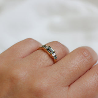 Yellow gold ring with a teal green emerald cut sapphire, on hand, top view