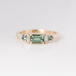Yellow gold ring with a teal green emerald cut sapphire, front view