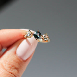 Blue Cushion Cut Montana Sapphire Three Stone Ring being held in sunlight 