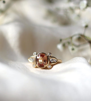 Custom engagement ring with ethically sourced orange sapphire centre stone in a gold setting, with clustered accent diamonds.