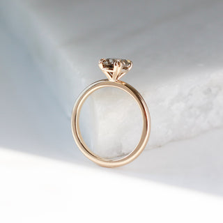 Oval cut champagne sapphire ring in yellow gold on marble profile view
