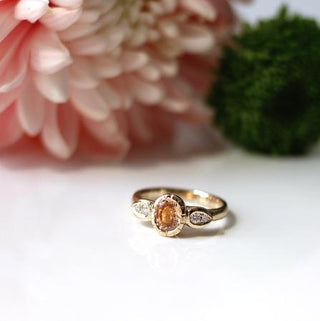 Custom engagement ring with ethically sourced peach sapphire centre stone in a gold setting, handcrafted by Yuliya Chorna at her Toronto studio.