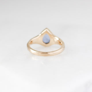 Gold ring with a blue stone on a light grey background
