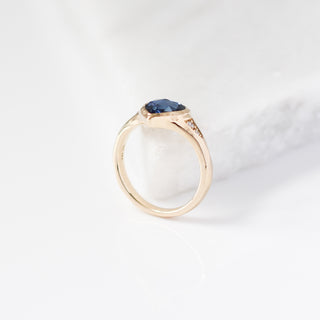Gold ring with a blue gemstone on a white background