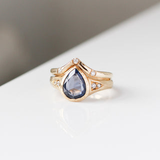 Gold ring with a teardrop-shaped gemstone on a light background
