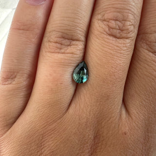 Pear cut teal green sapphire on finger
