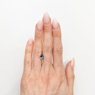 Pear cut teal green sapphire on hand