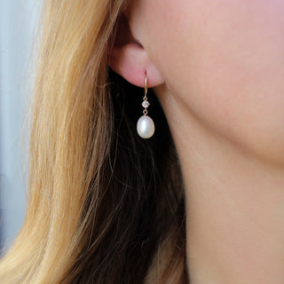 Pearl and diamond drop hoop earrings in ear
