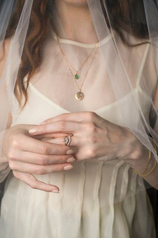 Close-up of a person wearing gold jewelry with a veil in the background