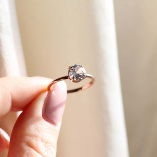 round white sapphire solitaire engagement ring held up in three quarter view in the sun