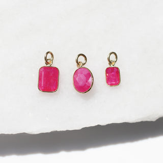 Large Ruby Bezel Charms on marble in sunlight detailed front view