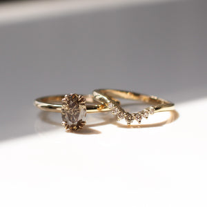 Grey Diamond stacking band in yellow gold paired with oval diamond gold ring in sunlight front view