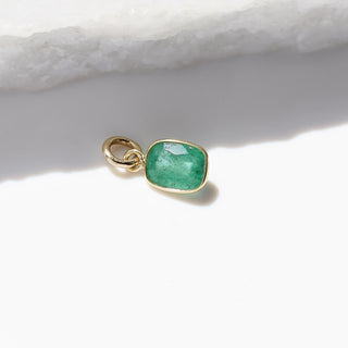 Small Emerald Bezel Charm side view in sunlight with marble