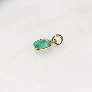 Small Emerald Bezel Charm quarter side view on marble