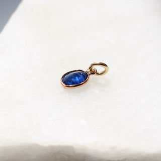 Blue Sapphire Bezel Charm quarter side view on marble 