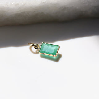 Small Emerald Bezel Charm quarter side view with marble in sunlight 
