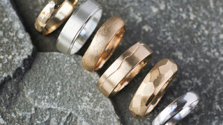 Set of gold and white gold rings on a textured stone surface