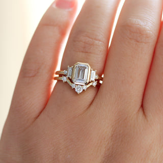 Bezel five-stone white diamond engagement ring with a white diamond wedding band on hand, both in yellow gold