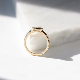 Yellow gold ring with a bezel set white oval cut diamond, side view